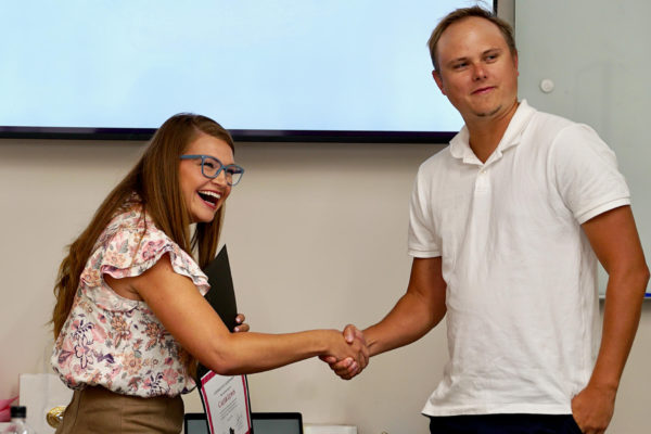 Caleb, senior developer, receives an award from Caley, chief business officer