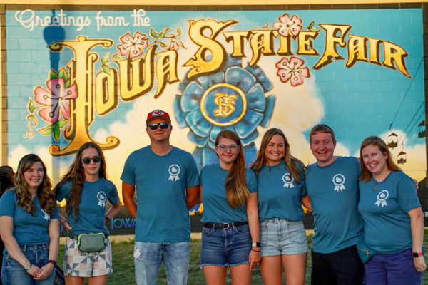 The Neapolitan Labs team takes a photo in front of a mural at the 2021 Iowa State Fair