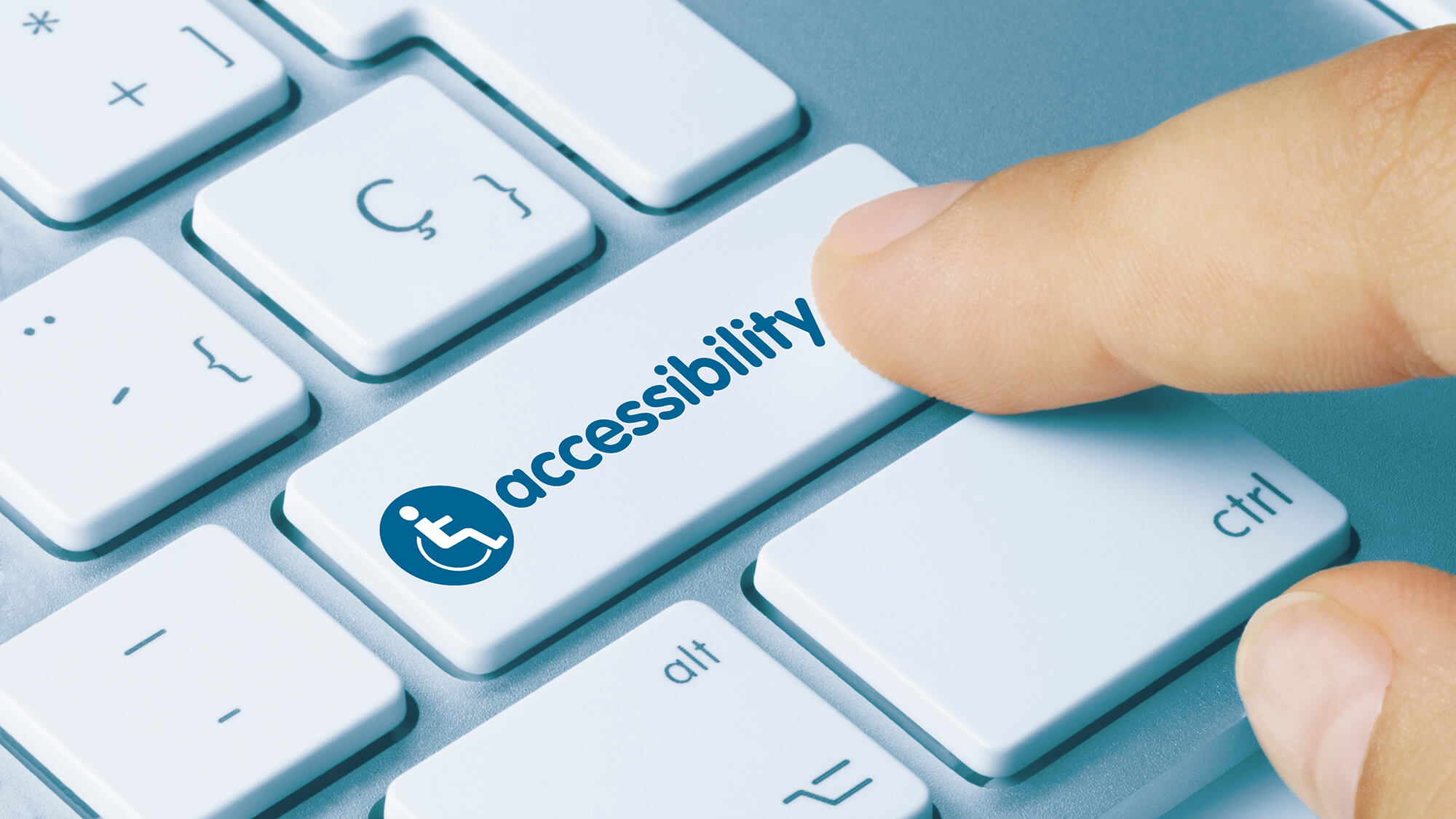 Hand clicking an "accessibility" key on a keyboard.