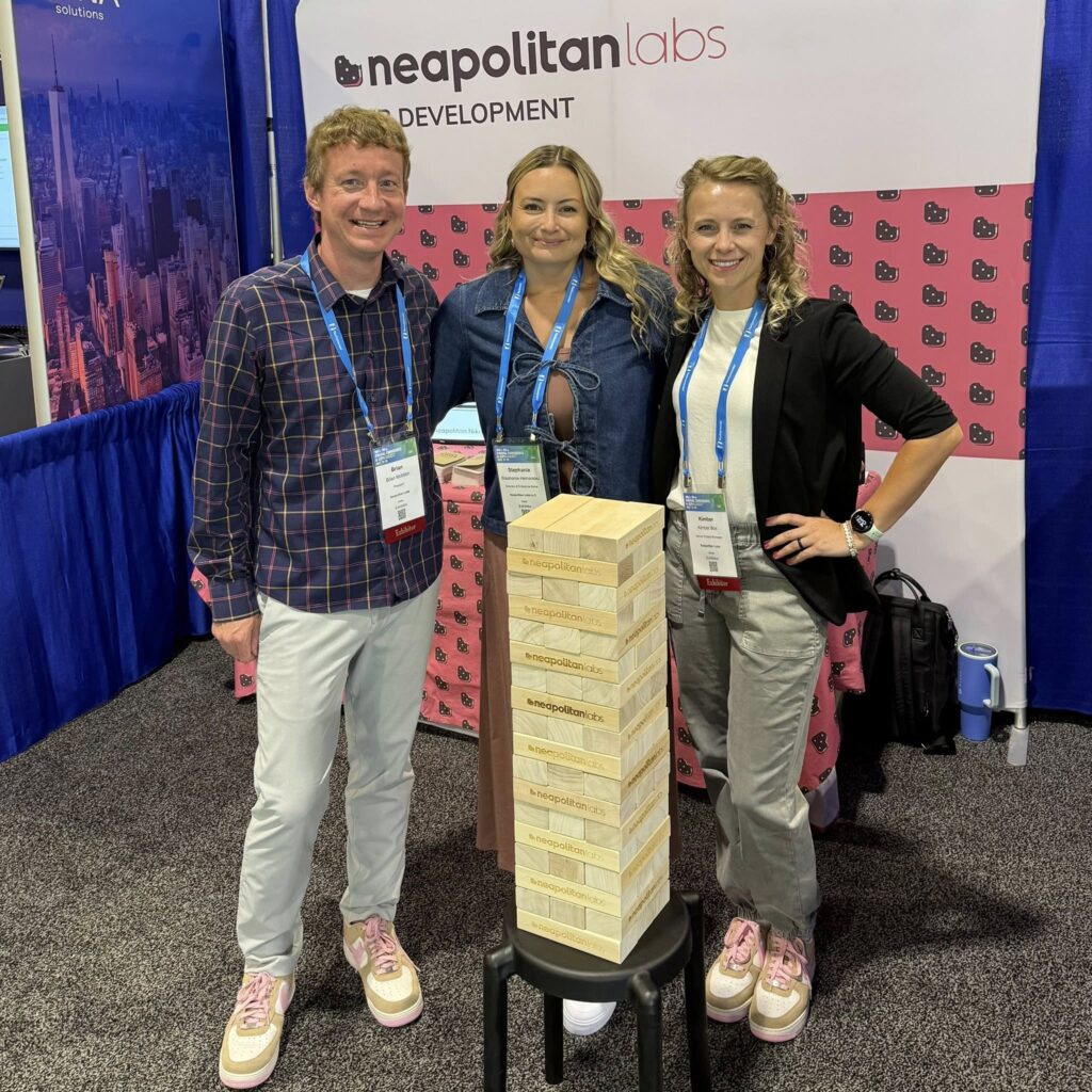 Team members Brian, Stephanie, and Kimber at a conference with a giant Jenga set.